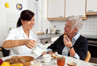 caregiver and a senior woman having a meal